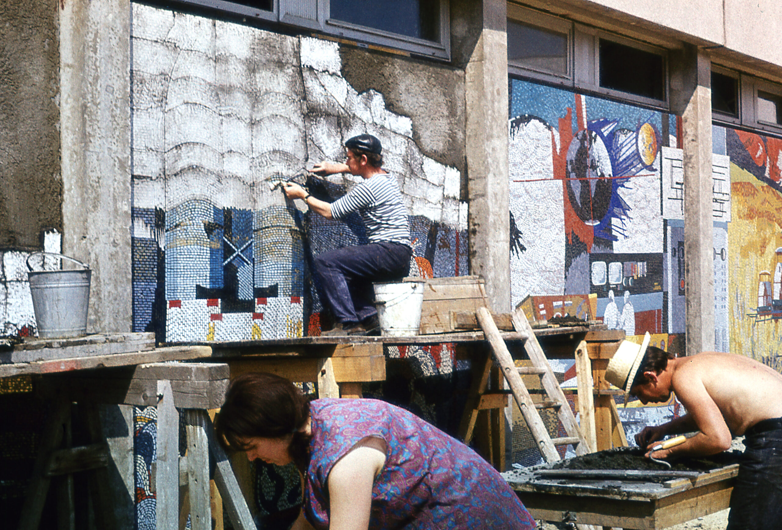 Ein Foto, auf dem drei Menschen die Detailflächen einer Mosaiktafel anbringen