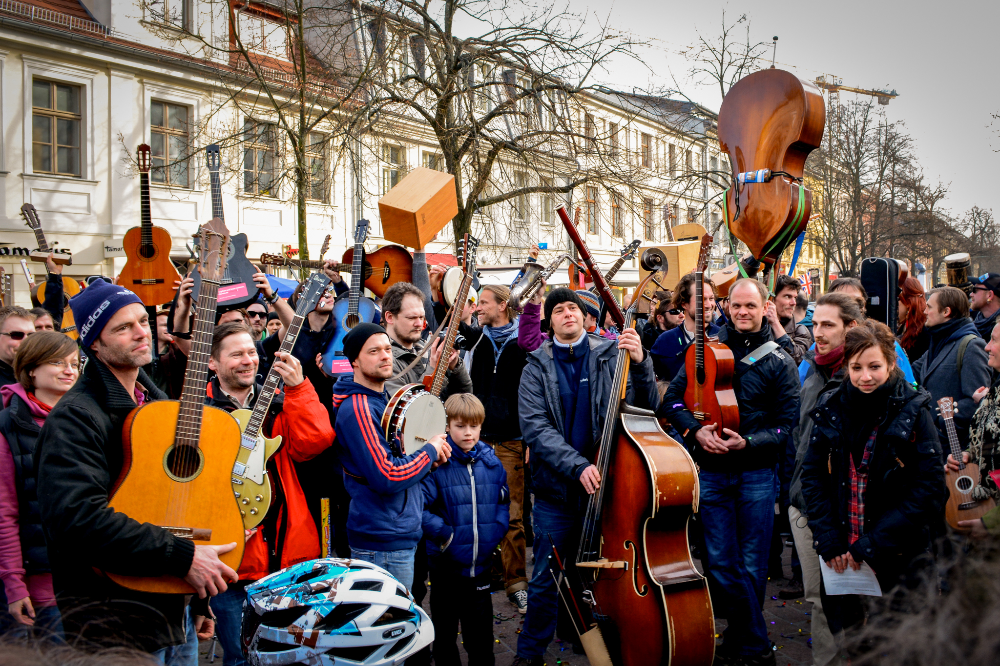 Ein Foto einer Menschenmenge in der Fußgängerzone. Viele Personen halten Gitarren und andere Instrumente hoch.